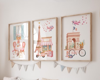 May include: Three framed watercolor prints depicting Parisian scenes. The prints feature the Eiffel Tower, a cafe, and the Arc de Triomphe, all in soft pink and pastel colors. A pink airplane and hearts accent the images. The frames are a light wood color.