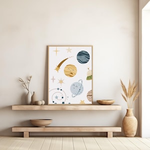 K&ouml;nnte beinhalten: Ein wei&szlig;er Hintergrund mit einer fantasievollen Illustration von Planeten, Sternen und einem Kometen. Die Planeten haben l&auml;chelnde Gesichter und sind in Blaut&ouml;nen, Gelb und Braun gehalten. Die Sterne sind golden und rosa.