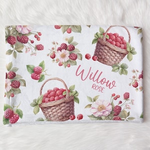 May include: White blanket with a repeating pattern of red raspberries, green leaves, and pink flowers. Two woven baskets filled with raspberries are featured. The name "Willow Rose" is written in pink script.