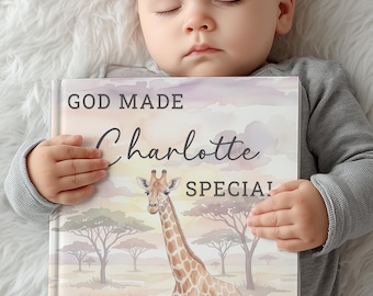 May include: A personalized children's book with the text "GOD MADE Charlotte SPECIAL!" features a watercolor illustration of a giraffe in a savanna landscape. The book is held by a baby wearing a gray long-sleeved shirt.