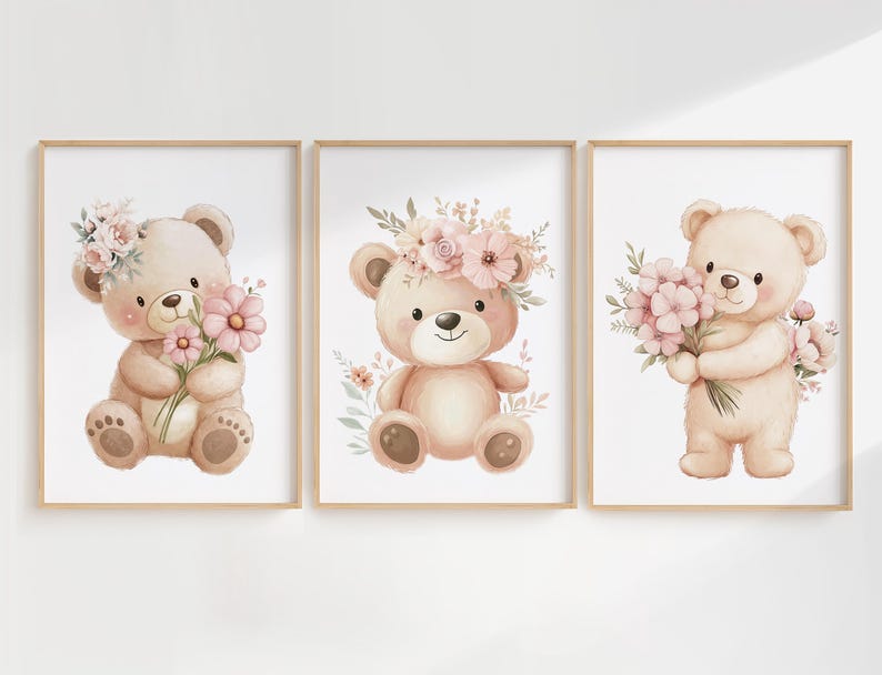 May include: Set of three framed watercolor prints featuring adorable teddy bears. Each bear is depicted in soft, pastel colors, holding or adorned with pink flowers and floral accents. The prints are set against a white background.