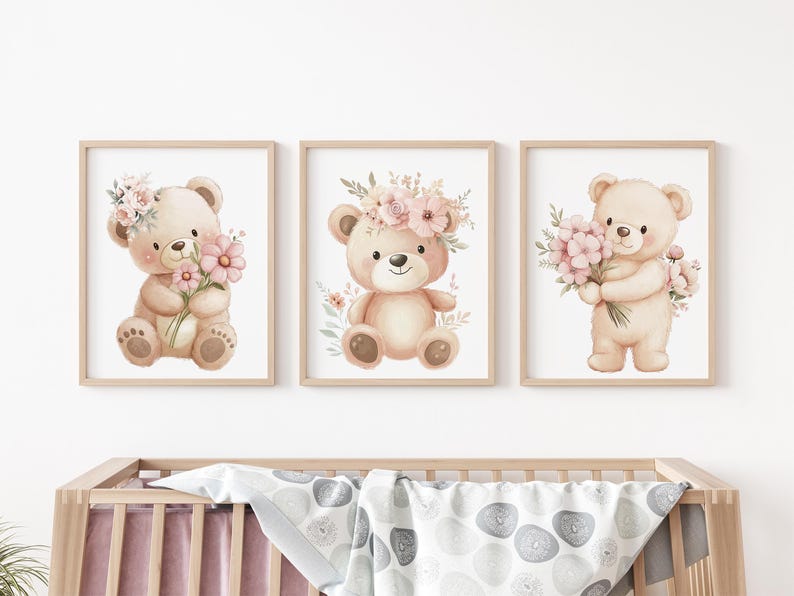 May include: Set of three framed watercolor prints featuring adorable teddy bears. Each bear is depicted with a floral crown or holding a bouquet of pink flowers. The artwork has a soft, pastel color palette, perfect for a nursery or children's room.