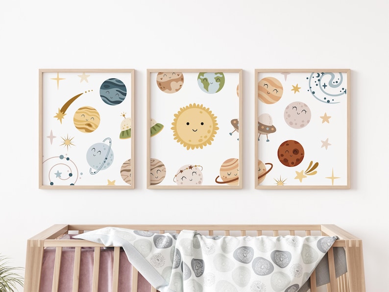 K&ouml;nnte beinhalten: Drei gerahmte Drucke mit wei&szlig;em Hintergrund und bunten Illustrationen von Planeten und Sternen. Die Planeten haben l&auml;chelnde Gesichter und sind von Sternen und Kometen umgeben.