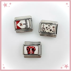 Puede incluir: Tres eslabones modulares rectangulares para pulsera hechos de acero inoxidable. Un eslabón presenta el logotipo rojo y blanco de Marlboro, otro muestra notas musicales y estrellas negras sobre fondo blanco, y otro muestra guantes de boxeo rojos.