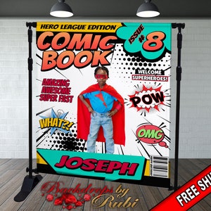 May include: A comic book themed backdrop with a superhero child in a red cape and blue shirt. The backdrop is white with black and red comic book speech bubbles. The text on the backdrop reads "Hero League Edition Comic Book Issue #8" and "Welcome Superheroes!" with the name "Joseph" at the bottom.