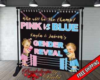 Puede incluir: Un telón de fondo negro para una revelación de género con temática de ring de boxeo. Presenta un guante de boxeo rosa y azul, dos bebés con atuendo de boxeo y el texto "Who will be The Champ? PINK vs BLUE Kayla & Jairon's GENDER REVEAL".