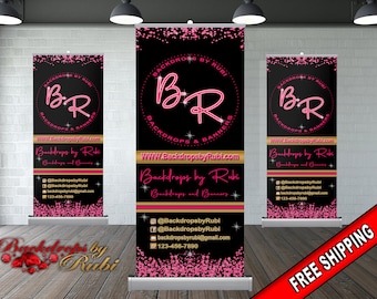 May include: Three black retractable banner stands with pink glitter and gold accents. The banners advertise a business called "Backdrops by Rubi" and include the website address "www.BackdropsbyRubi.com", social media handles, and a phone number.