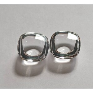May include: Two clear glass square-shaped beads with a hollow center.