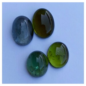 May include: Four oval-shaped gemstones, two green and two blue, on a light blue background.