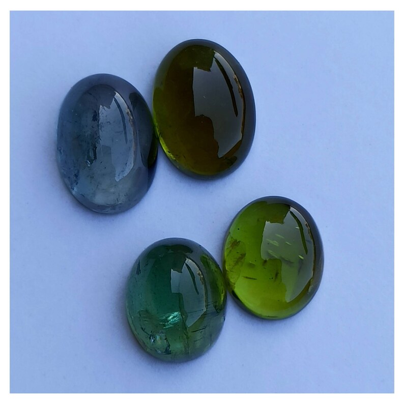 May include: Four oval-shaped gemstones, two green and two blue, on a light blue background.