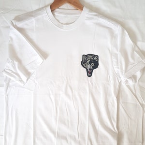 May include: White t-shirt with a black and gray wolf graphic on the front.