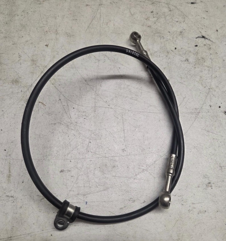 May include: A black motorcycle brake line with silver fittings. The line is curved and has the number "2023185" printed on it. The brake line is designed to connect to a motorcycle's braking system.