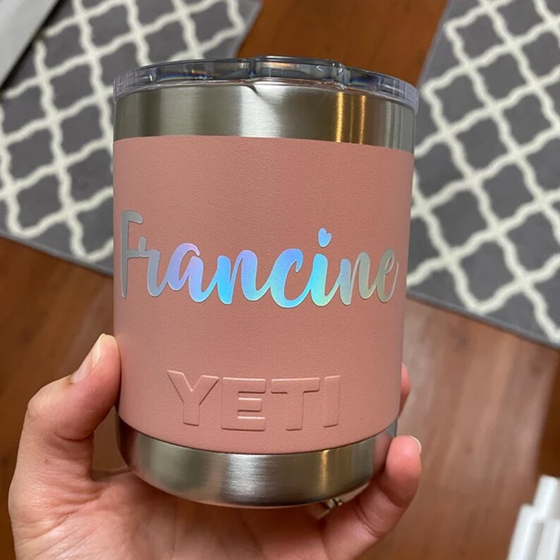 A person's hand holding a pink and silver insulated coffee cup with the name "Francine" printed on it.