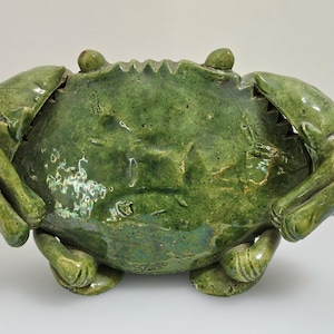 May include: A ceramic crab sculpture in shades of green. The crab has a textured surface and detailed claws and legs. The sculpture is a decorative item, likely for home decor.