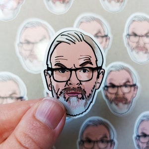 May include: A white sticker featuring a cartoon illustration of a person with a white beard and glasses. The person is wearing a white shirt and has a serious expression.