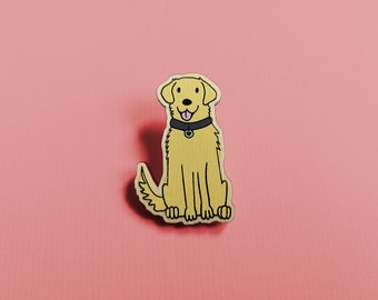 May include: A yellow wooden pin of a golden retriever dog wearing a black collar. The dog is sitting with its tongue sticking out.