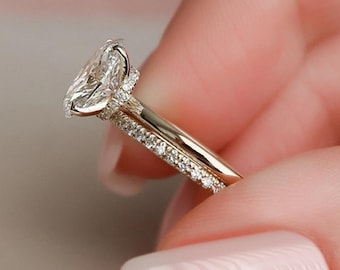 May include: A gold engagement ring with a large oval-shaped diamond center stone and a pave diamond band.