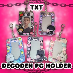 Puede incluir: Cinco portatarjetas Decoden con marcos transparentes decorados con cuentas, abalorios e ilustraciones de personajes. Los soportes están conectados por cadenas y llaveros plateados. El texto "TXT" y "DECODEN PC HOLDER" es visible.