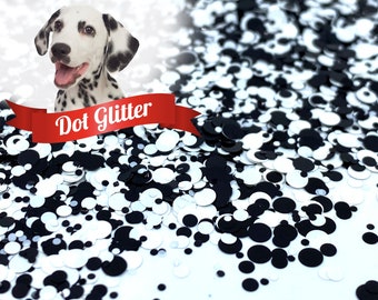 May include: Close-up of black and white dot glitter. The glitter is scattered across a white surface. A Dalmatian dog is in the background. The text "Dot Glitter" is on a red banner.