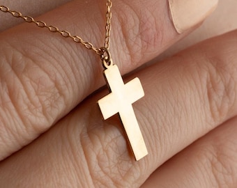 May include: A gold chain necklace with a simple gold cross pendant.