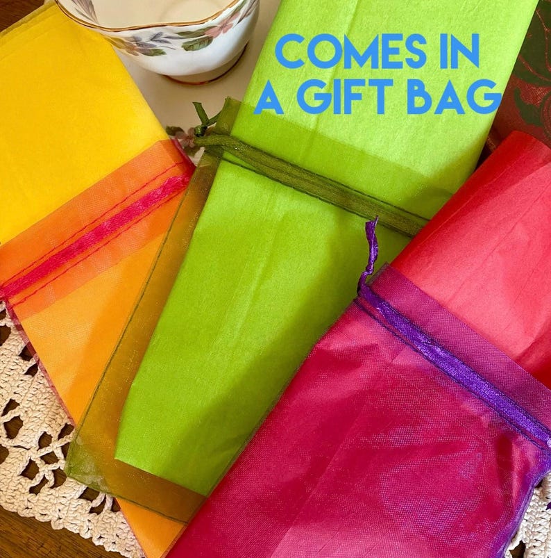 Pu&ograve; includere: Quattro sacchetti regalo di diversi colori, giallo, verde, rosso e viola, con il testo "Comes in a gift bag" sul sacchetto verde.