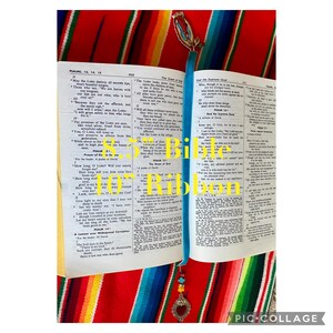 May include: An open Bible with a blue ribbon bookmark. The bookmark has a heart-shaped charm with beads. The Bible pages are open to Psalms 13, 14, and 15.