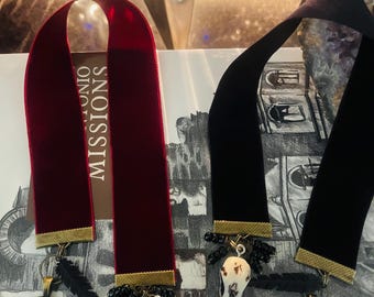 May include: Two velvet bookmarks with gold trim and raven charms. The charms feature a black raven with a quote from Edgar Allan Poe: "I became insane, with long intervals of horrible sanity."