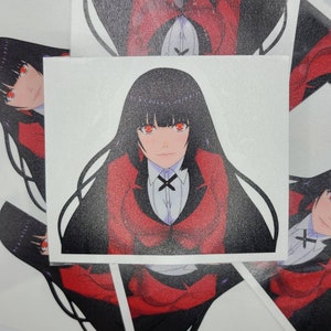 May include: A stack of white stickers featuring a manga-style illustration of a character with long black hair, red eyes, and a red blazer over a white shirt. The character has a stern expression.