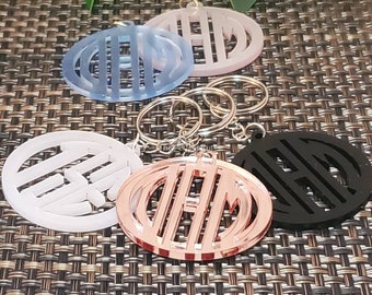 May include: Five different colored keychains with a circle design featuring the letters "EHM" in a cutout style. The keychains are made of acrylic and come in white, black, light blue, pink, and rose gold.