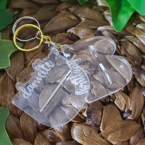 May include: Clear acrylic keychain with the words "Danielle" and "Mommy" engraved on it. The keychain is attached to a gold and silver split ring.