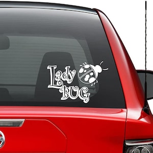 May include: White vinyl decal with the words "Lady Bug" in a stylized font. A ladybug silhouette is next to the words.