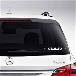 May include: White silhouette of a plane with four propellers on the back window of a silver car. The car has a black rear window and the text "4MATIC" is visible on the back of the car.