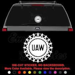 May include: White vinyl die-cut sticker with a circle design featuring the text "UAW" in a bold font. The circle is surrounded by a ring of pointed stars. The sticker has no background.