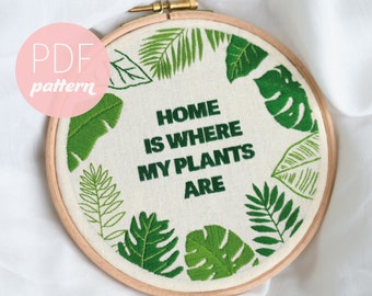 May include: Embroidered hoop art with green leaves and the text "Home is where my plants are".