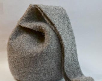 May include: A gray felt hat with a rounded body and a long, pointed flap. The hat is made of a soft, textured material and is likely handmade. The hat is a solid gray color and is suitable for a costume or everyday wear.