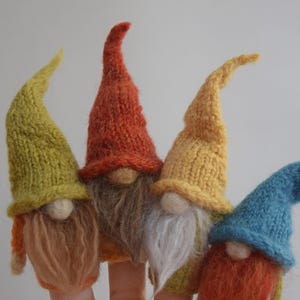 May include: Four handmade gnome finger puppets with knitted hats in yellow, orange, and blue. Each gnome has a fluffy beard in shades of brown, white, and orange. The puppets are designed to fit on fingers.