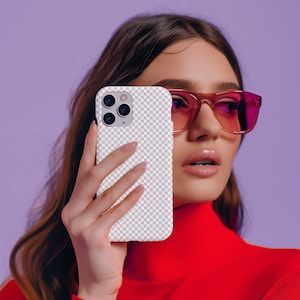 Op de afbeelding: Een vrouw met een rode trui met hoge hals en roze zonnebril houdt een witte iPhone-hoes met een transparante achterkant en een uitsparing voor de camera vast. De hoes heeft een geruit patroon.