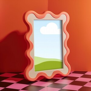 May include: A pink and white picture frame with a wavy border. The frame is empty and has a white mat. The frame is sitting on a black and pink checkered surface.