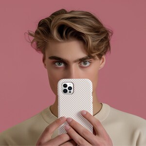 May include: A person is holding a white phone case with a checkered pattern and a camera lens on the back.
