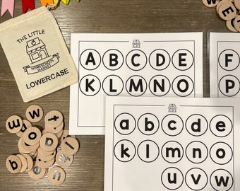 May include: A set of lowercase alphabet letter tiles with a white background and black lettering. The tiles are arranged in a circle with the letters A through Z. The tiles are on a wooden surface. The image also includes a small bag with the text "The Little Homeschool Market" and "Lowercase" printed on it.