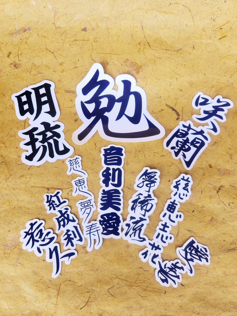 Puede incluir: Una colecci&oacute;n de caracteres kanji japoneses en blanco y negro sobre pegatinas blancas. Los caracteres est&aacute;n impresos en un estilo caligr&aacute;fico en negrita. Los caracteres son: 美優, 慈恵心, 勉, 志花, 舞饰流, 明琉, 紅成利, 惹久.