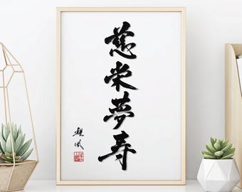 May include: Framed artwork featuring elegant black calligraphy on a white background. The calligraphy is vertical and includes several characters. The frame is a light wood color. A red stamp is in the lower left corner. The artwork is displayed on a white shelf.
