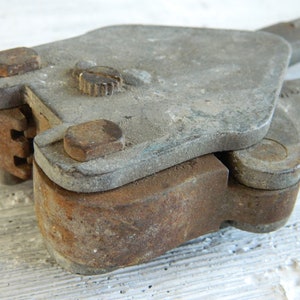 K&ouml;nnte beinhalten: Nahaufnahme eines rostigen Metallwerkzeugs mit Griff und Hebel. Das Werkzeug hat eine abgenutzte, graue Oberfl&auml;che und einen kleinen, runden Knopf oben.