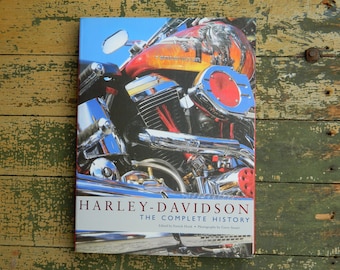 Könnte beinhalten: Nahaufnahme eines Harley-Davidson-Motorrads mit roter, orangefarbener und schwarzer Lackierung. Der Buchtitel lautet "Harley-Davidson The Complete History".