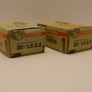 May include: Two brown cardboard boxes with red and white text. The boxes contain Schrader Valve Premium Tubes for bicycles. The boxes are labeled "Schwinn" and "20x1.5-2.2".