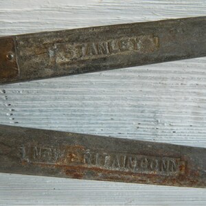 K&ouml;nnte beinhalten: Nahaufnahme von zwei rostigen Metallwerkzeugen mit dem aufgedruckten Text "F. Stanley & Co. New Britain, Conn.".