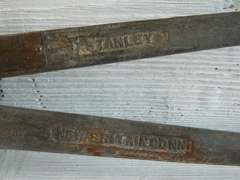 K&ouml;nnte beinhalten: Nahaufnahme von zwei rostigen Metallwerkzeugen mit dem aufgedruckten Text "F. Stanley & Co. New Britain, Conn.".