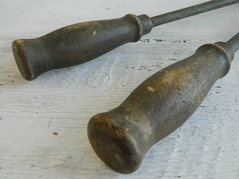 K&ouml;nnte beinhalten: Zwei antike Werkzeuge mit Holzgriffen und Metallstielen. Die Griffe sind dunkelbraun und haben ein abgenutztes, rustikales Aussehen.