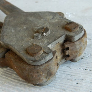 K&ouml;nnte beinhalten: Ein Vintage-Metallwerkzeug mit rostiger Oberfl&auml;che und einem Scharnier. Das Werkzeug hat an jeder Seite einen Griff und einen kleinen Knopf oben.