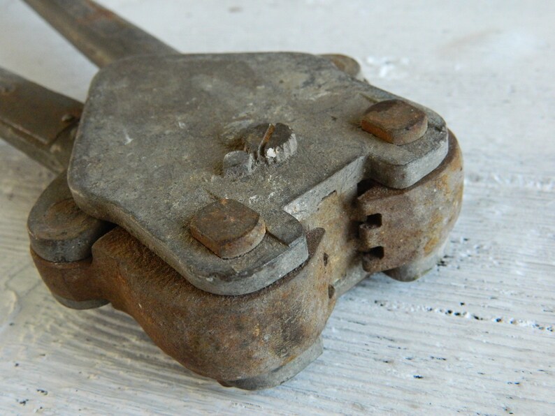 K&ouml;nnte beinhalten: Ein Vintage-Metallwerkzeug mit rostiger Oberfl&auml;che und einem Scharnier. Das Werkzeug hat an jeder Seite einen Griff und einen kleinen Knopf oben.